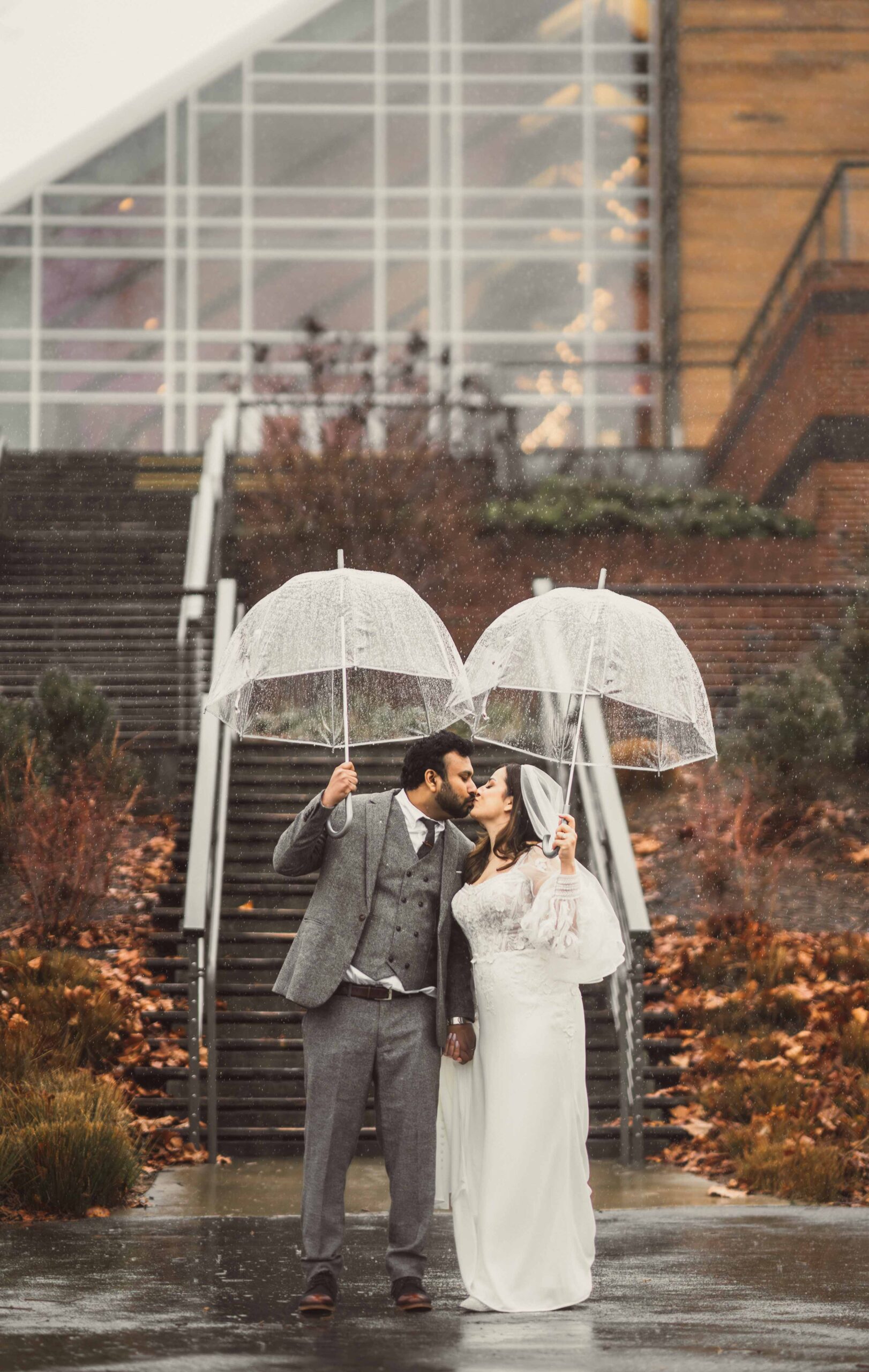 couples kiss in front of stairs at their River View at Occoquan wedding on a raining day