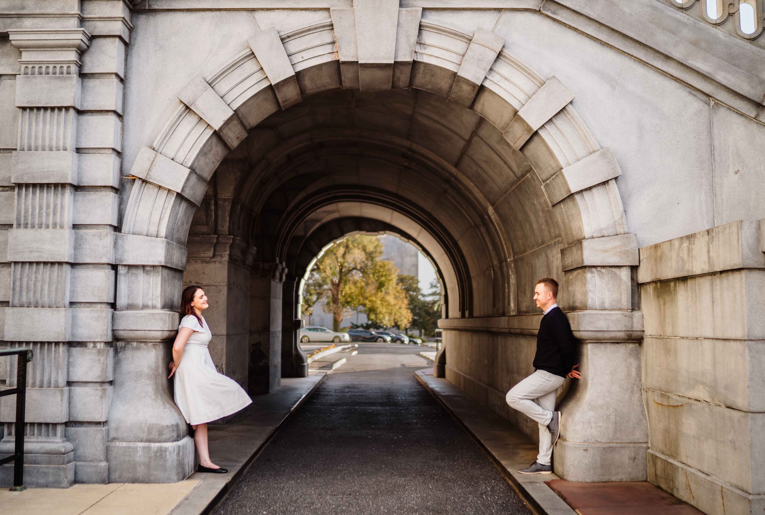 woman and man lean on the wall under the arch looking at each other at library of congress in DC