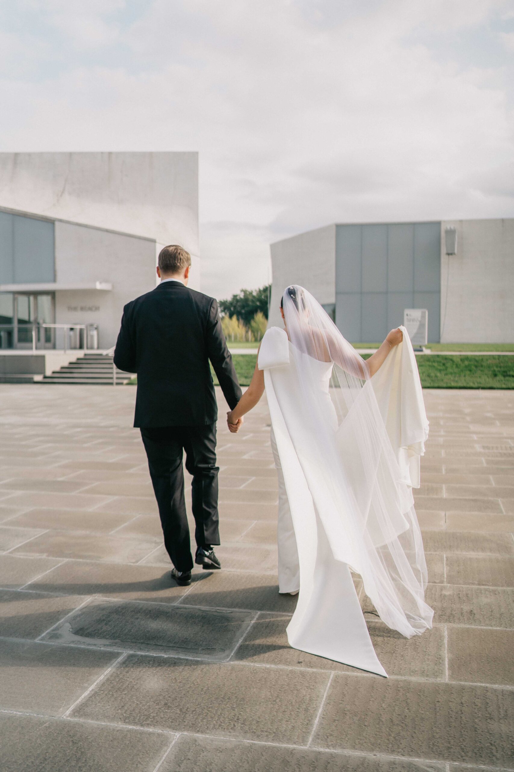 the back of groom holding bride's hand and walking