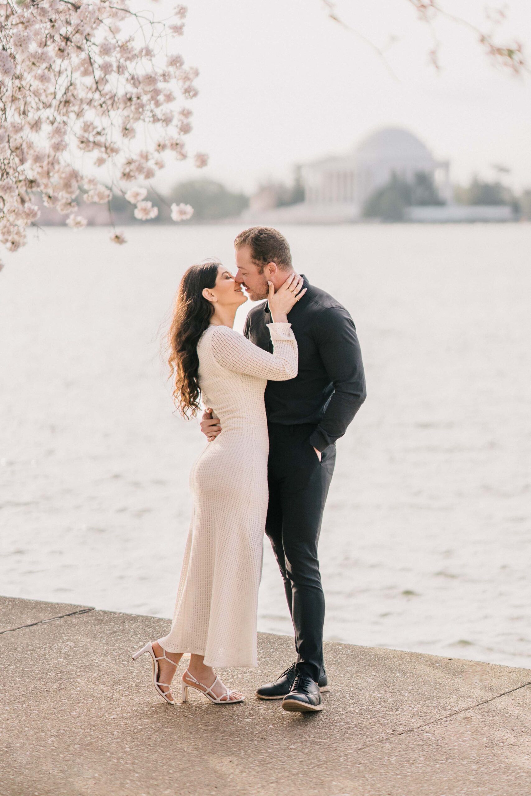 woman hold her boyfriend's face tenderly kissing by the lake full body engagement portrait