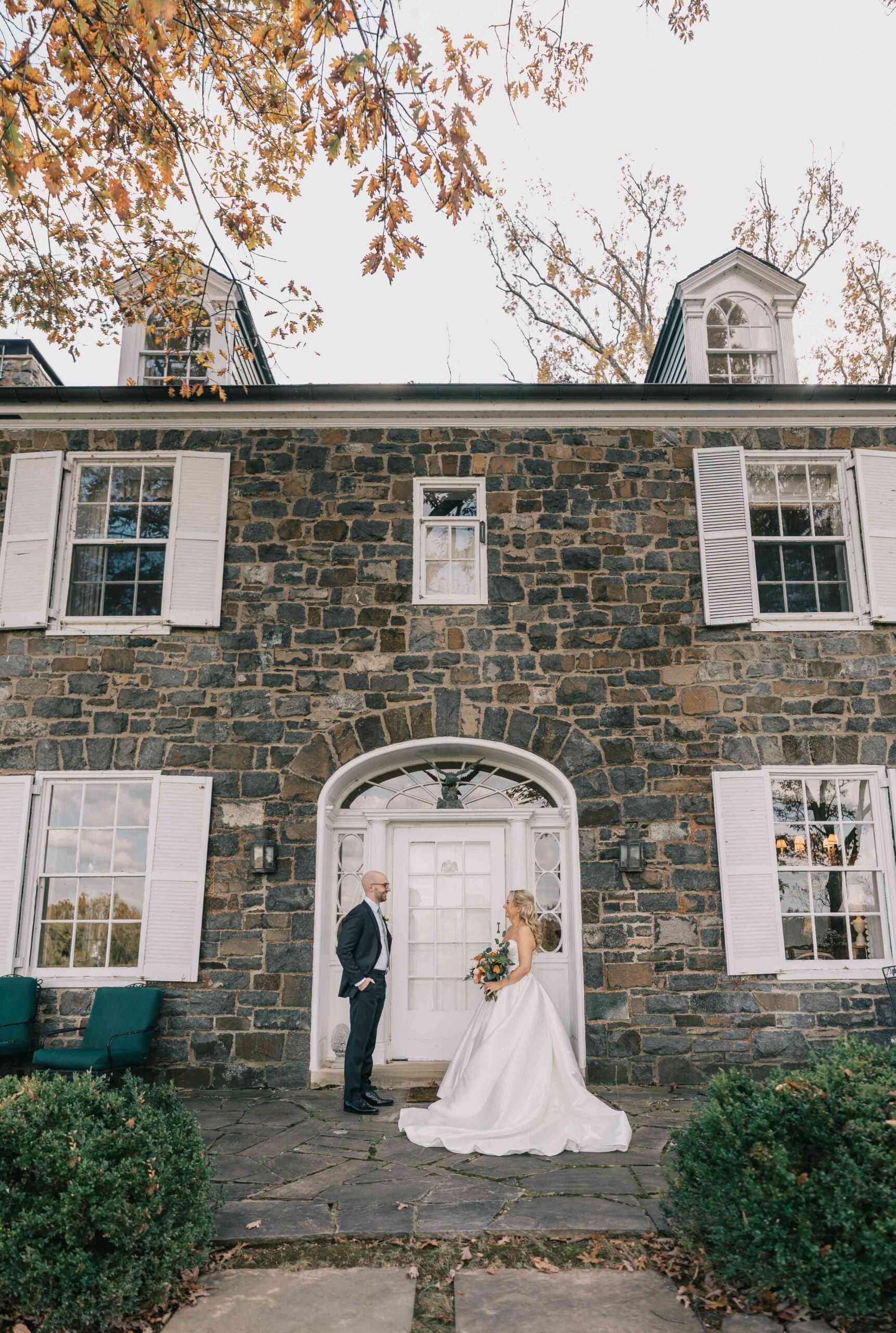 couple stands in front of Murray Hill Events stone wall building